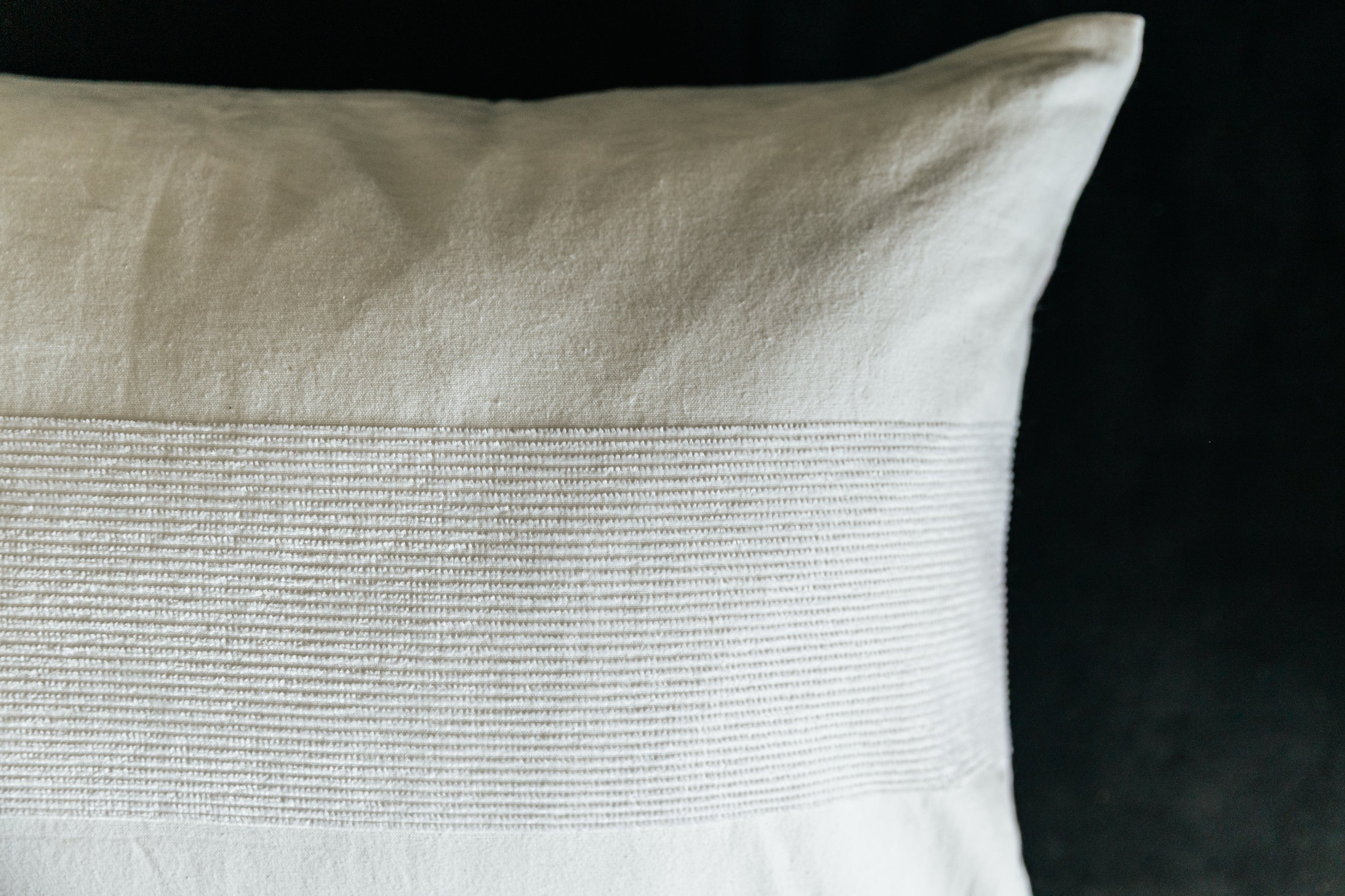 A close up on the exterior of a white lumbar pillow to show the textured detail.