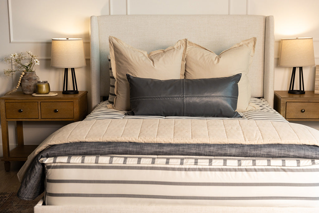 A queen bed made with white and black striped zipper bedding paired with neutral and black accessories.