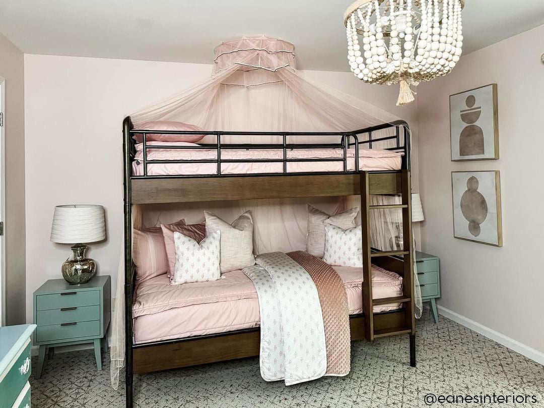 A  bunk bed with both bunks made with pink zipper bedding and light pink and floral pillows and blanket.