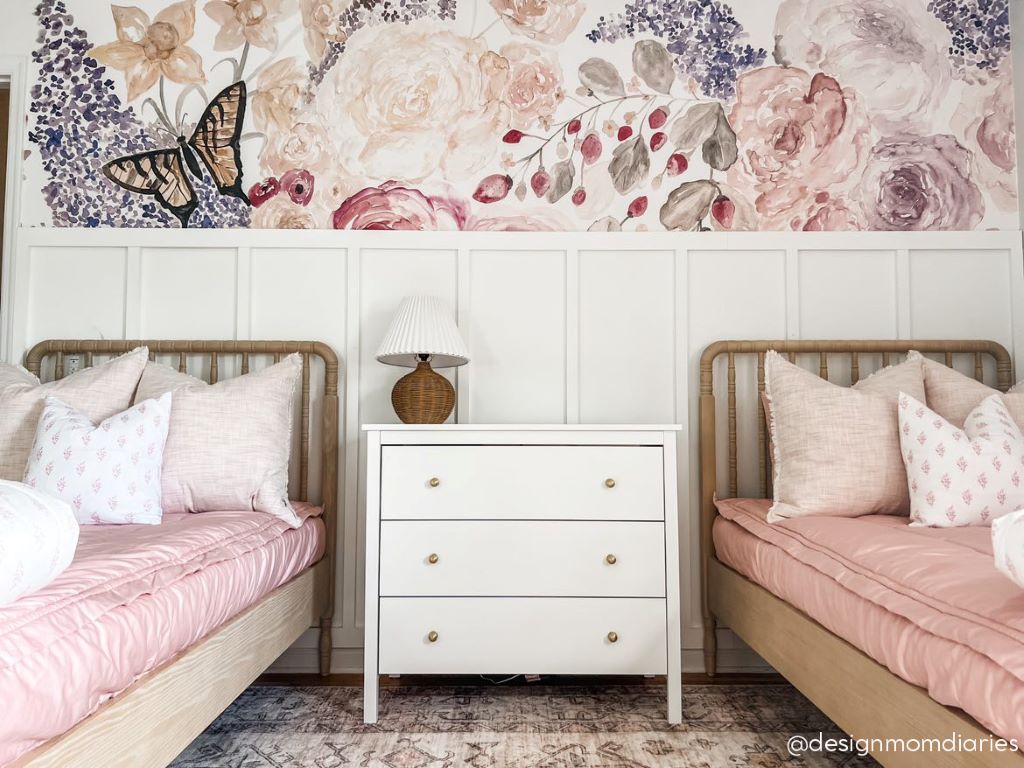 Two twin beds made with pink zipper bedding and adorned with light pink and floral pillows.