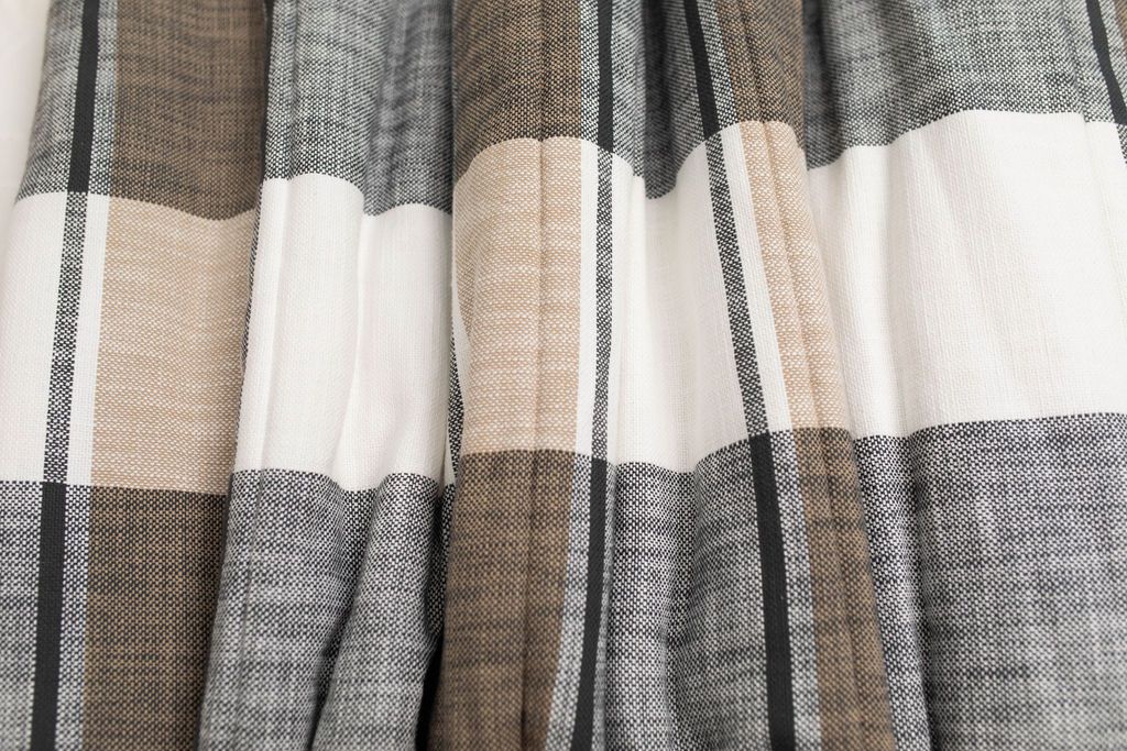 A close up of a cream, tan, and gray plaid pattern blanket.