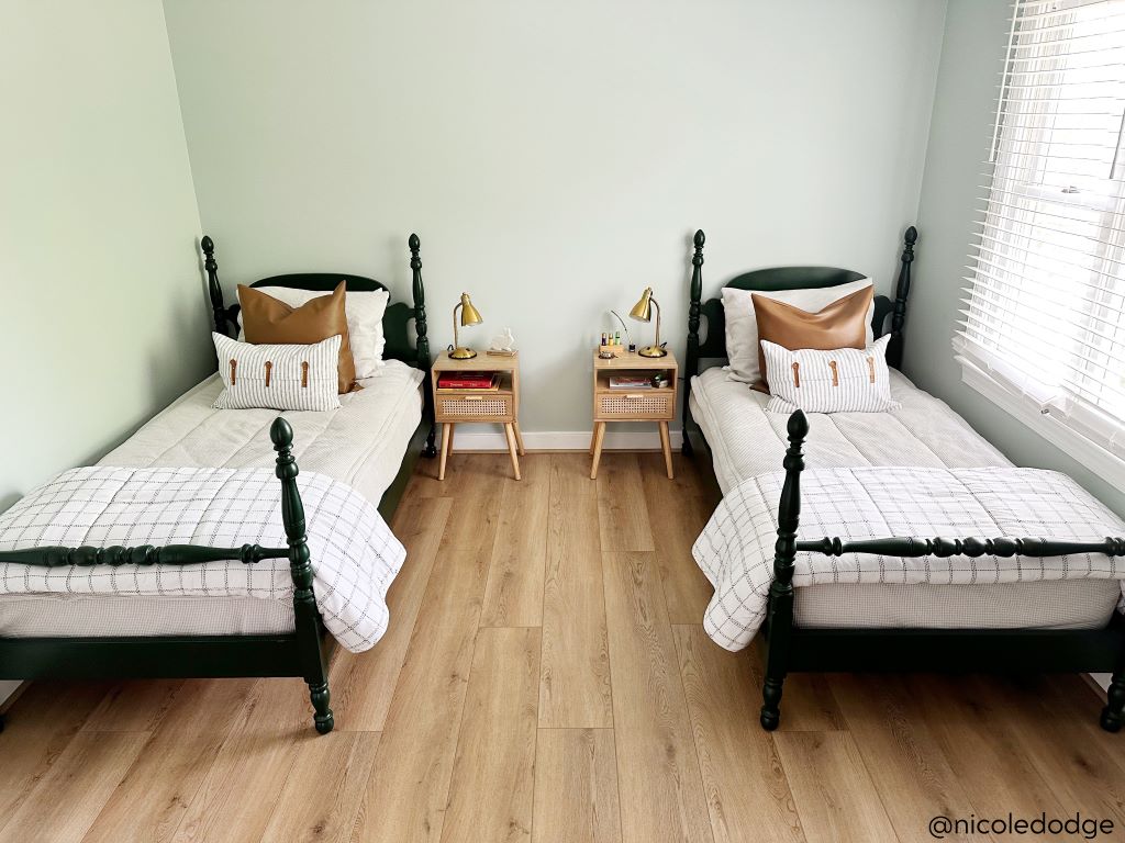 Two twin beds made with light gray waffle textured zipper bedding and an assortment of neutral and leather throw pillows and blankets.