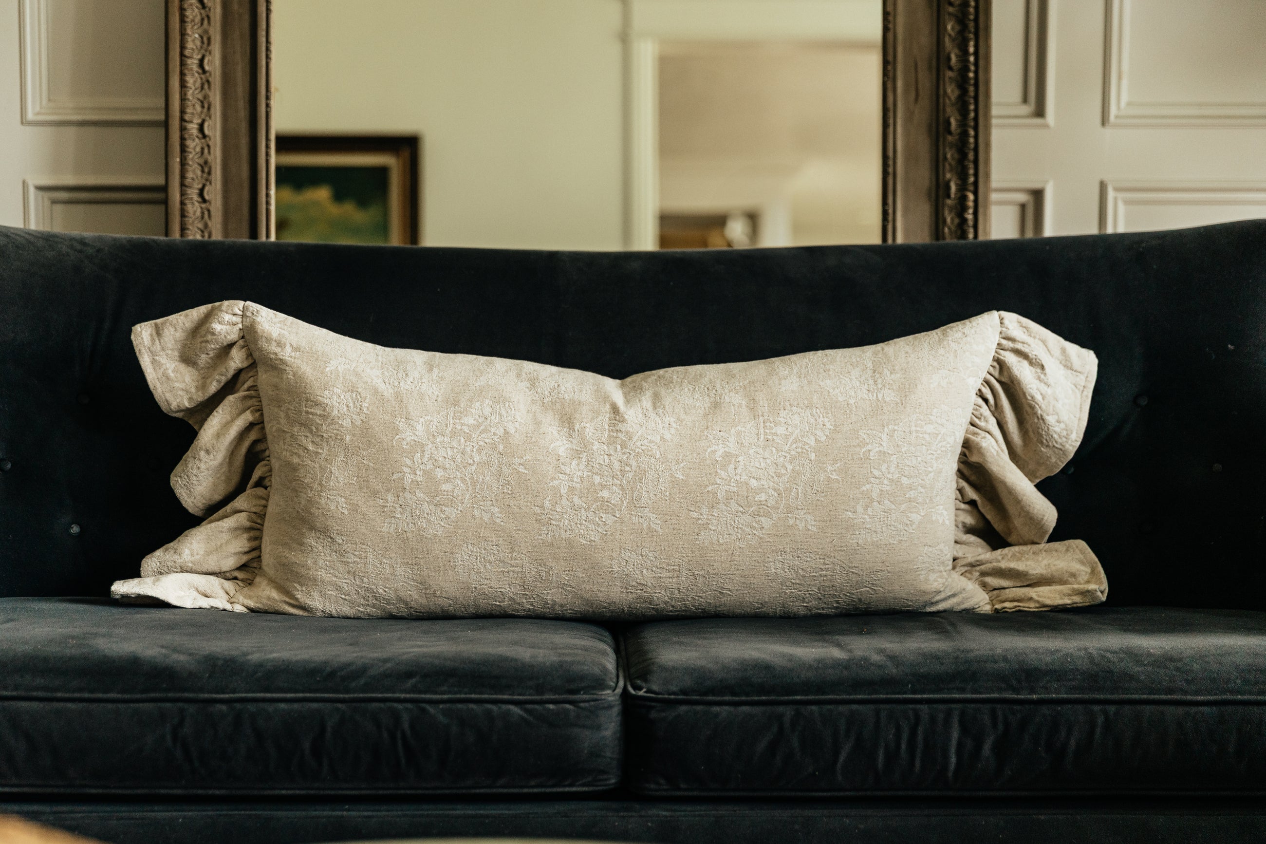 Tan lumbar pillow on black couch