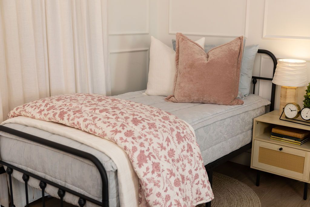 Twin bed with light blue floral zipper bedding with pink and cream accessories