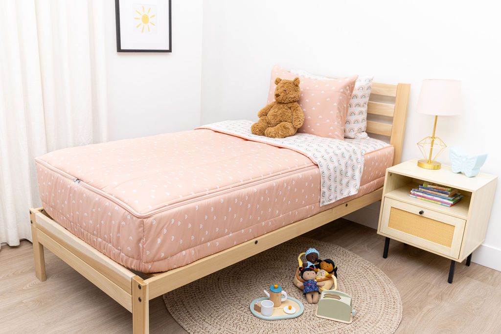 bedroom with twin bed decorated with peachy pink rainbow printed zipped bedding and toys on the ground