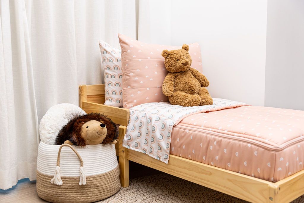 bedroom with toddler bed decorated with peachy pink rainbow printed zipper bedding