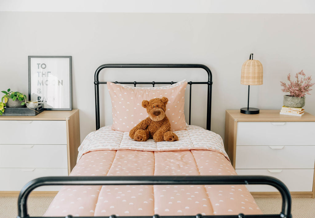 bedroom with twin bed decorated with peachy pink rainbow printed zipped bedding and teddy bear on the bed