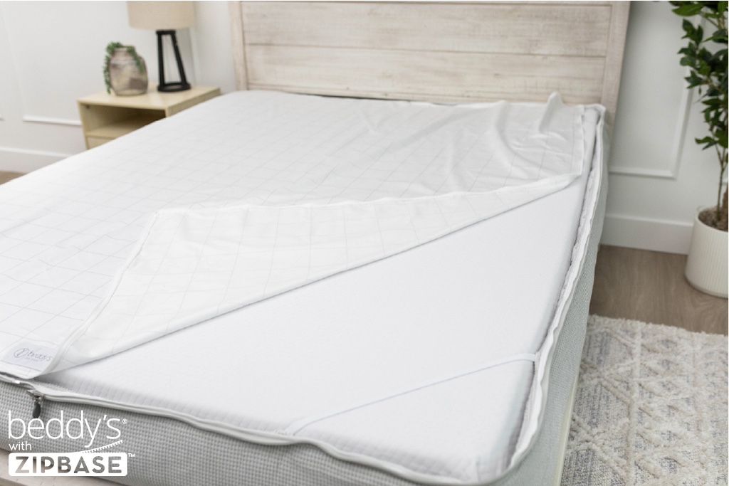 A ZipBase sheet partially unzipped and pulled back to show how it detaches from the rest of the base sheet wrapped around the sides of the mattress.