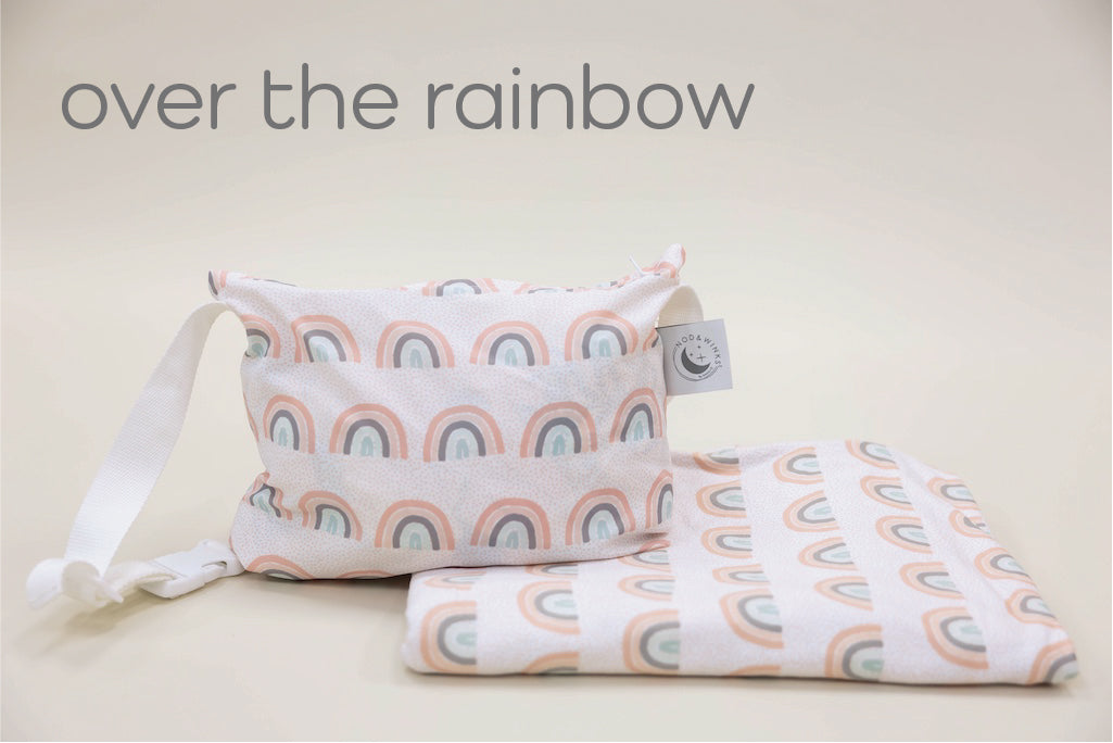 Kid travel blanket with rainbows and a coordinating pouch with a white strap.