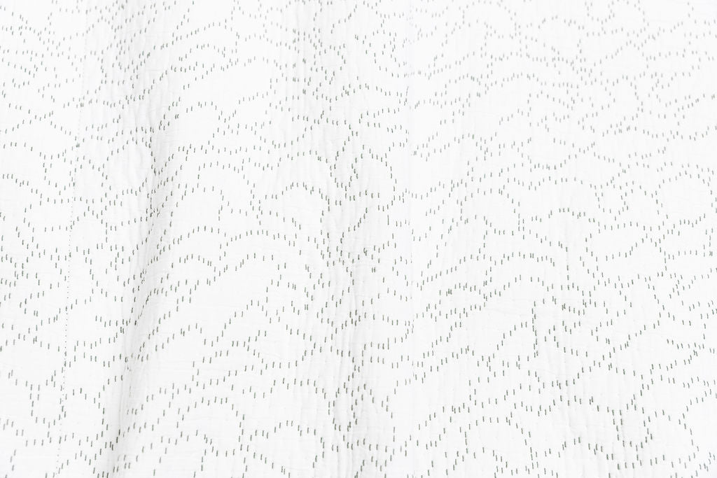 Close up of the white blanket with green stitching