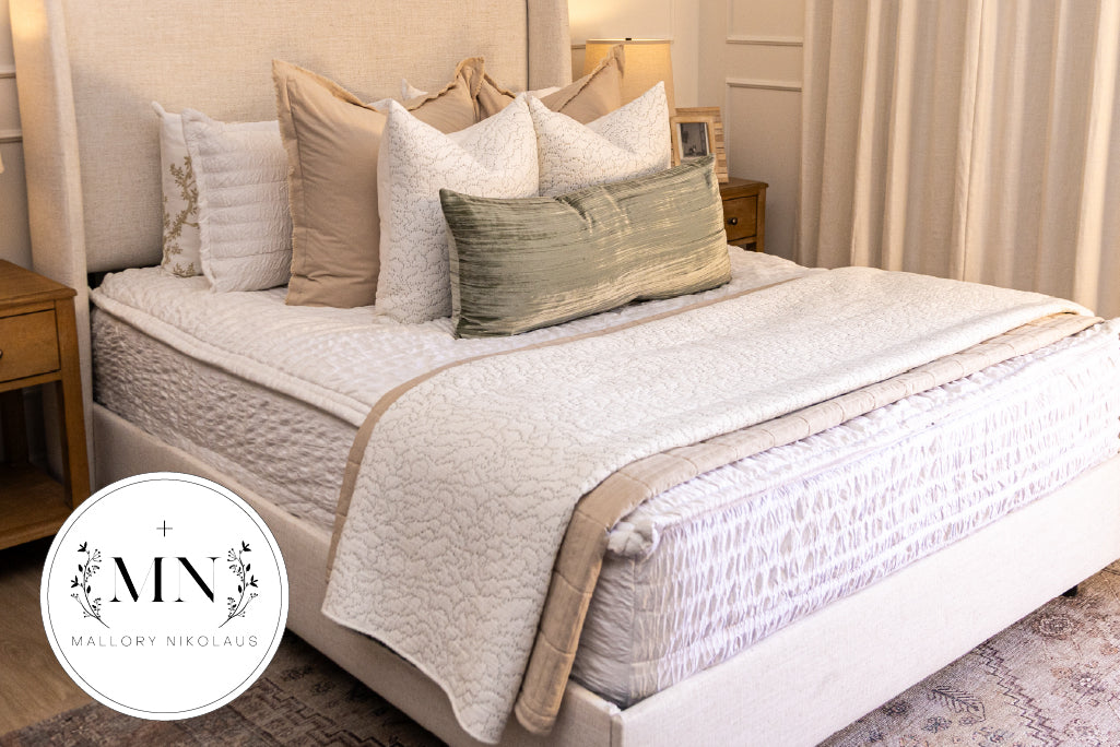 A bed made with seersucker white zipper bedding and an assortment of neutral throw pillows and blankets.