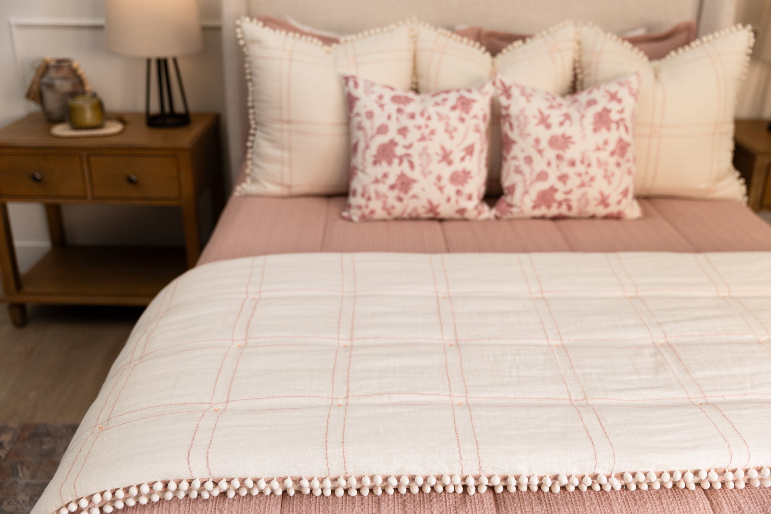 White Blanket with pink grid pattern and white pom pom edges