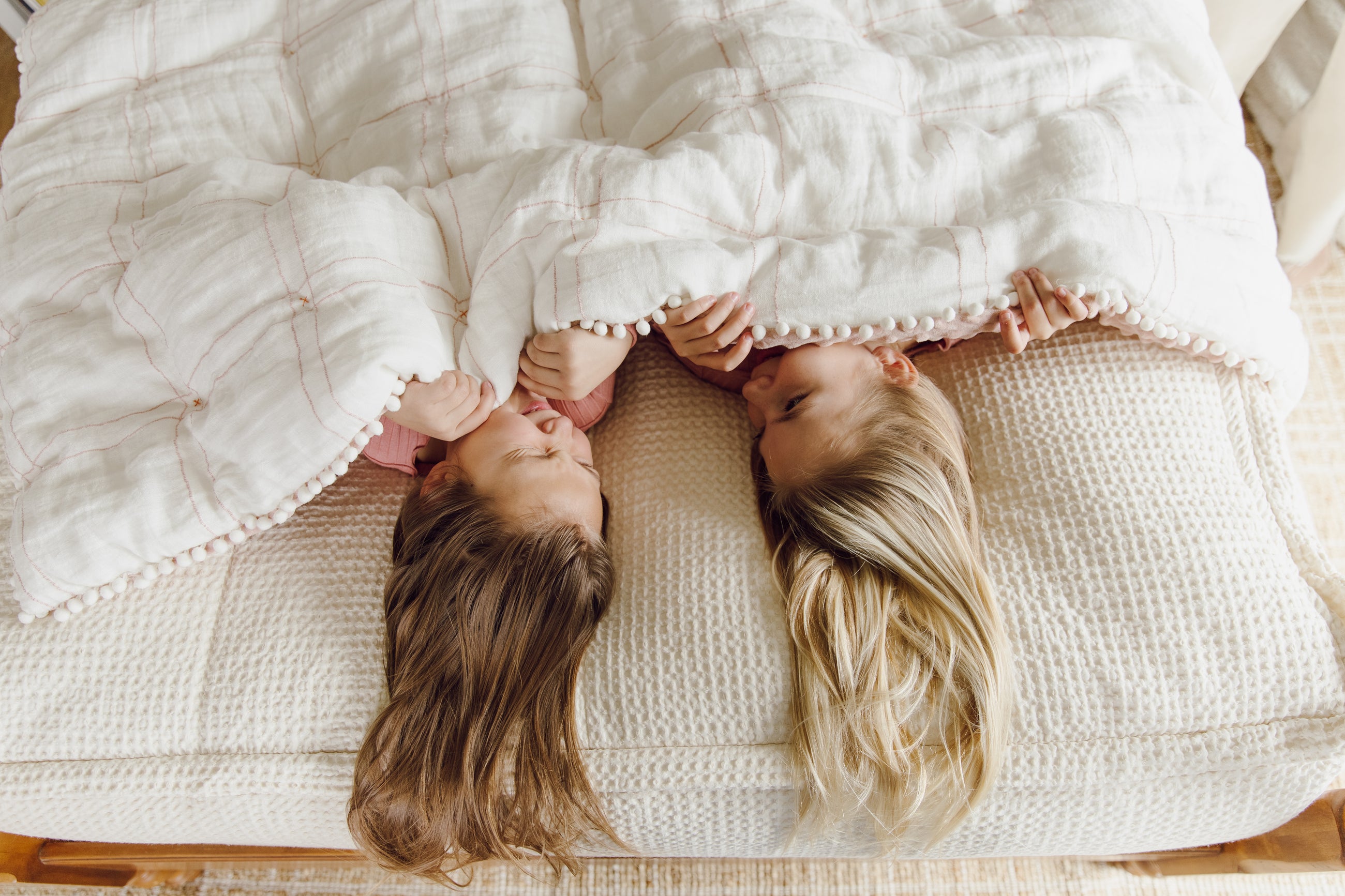 Two girls laughing while holding white blanket