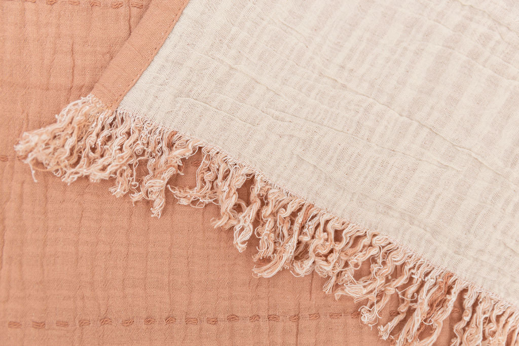 a close up of a terra cotta and pink dual sided throw blanket