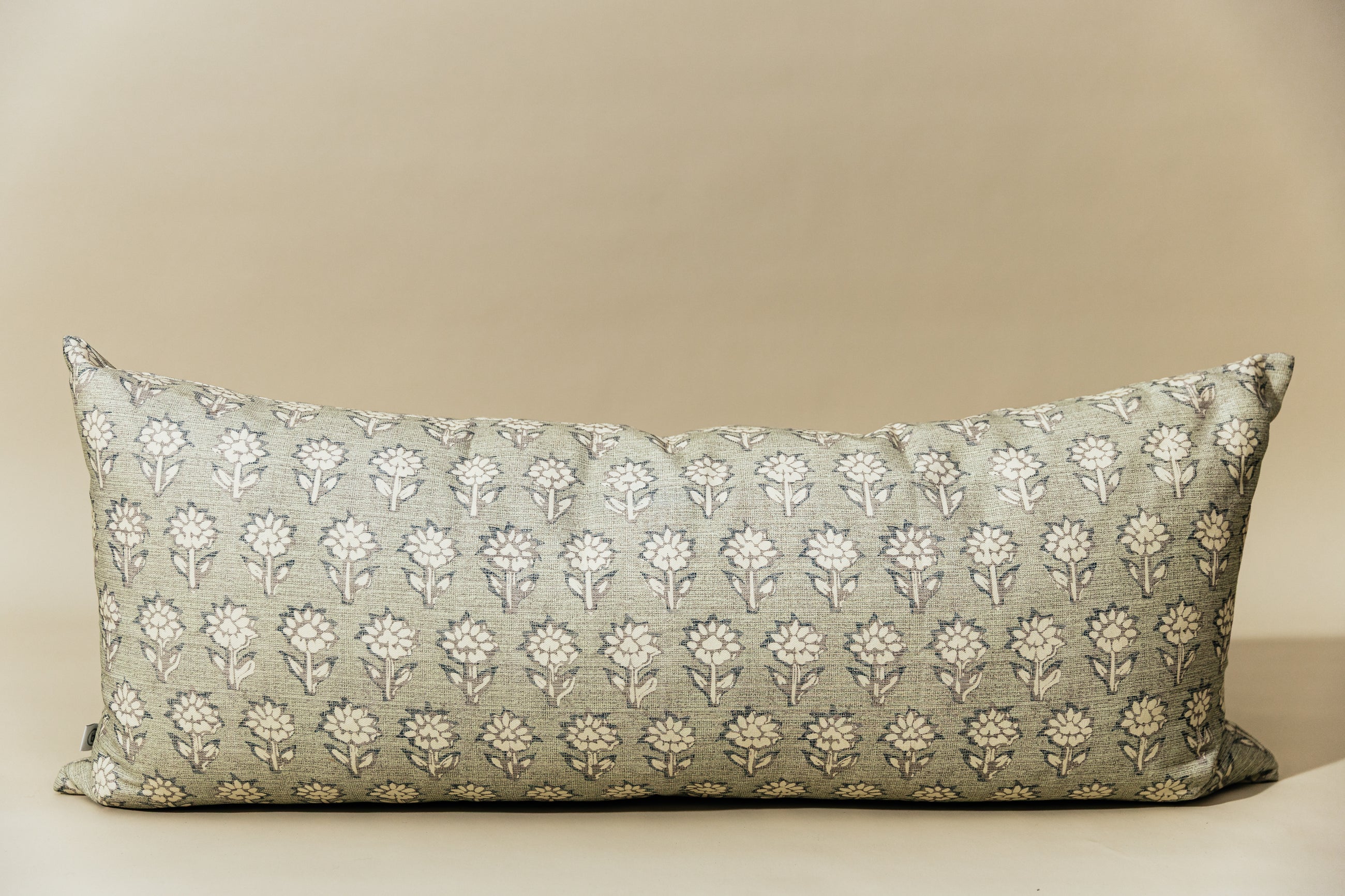 A sage green and blue floral pattern XL lumbar pillow arranged on a light green background.
