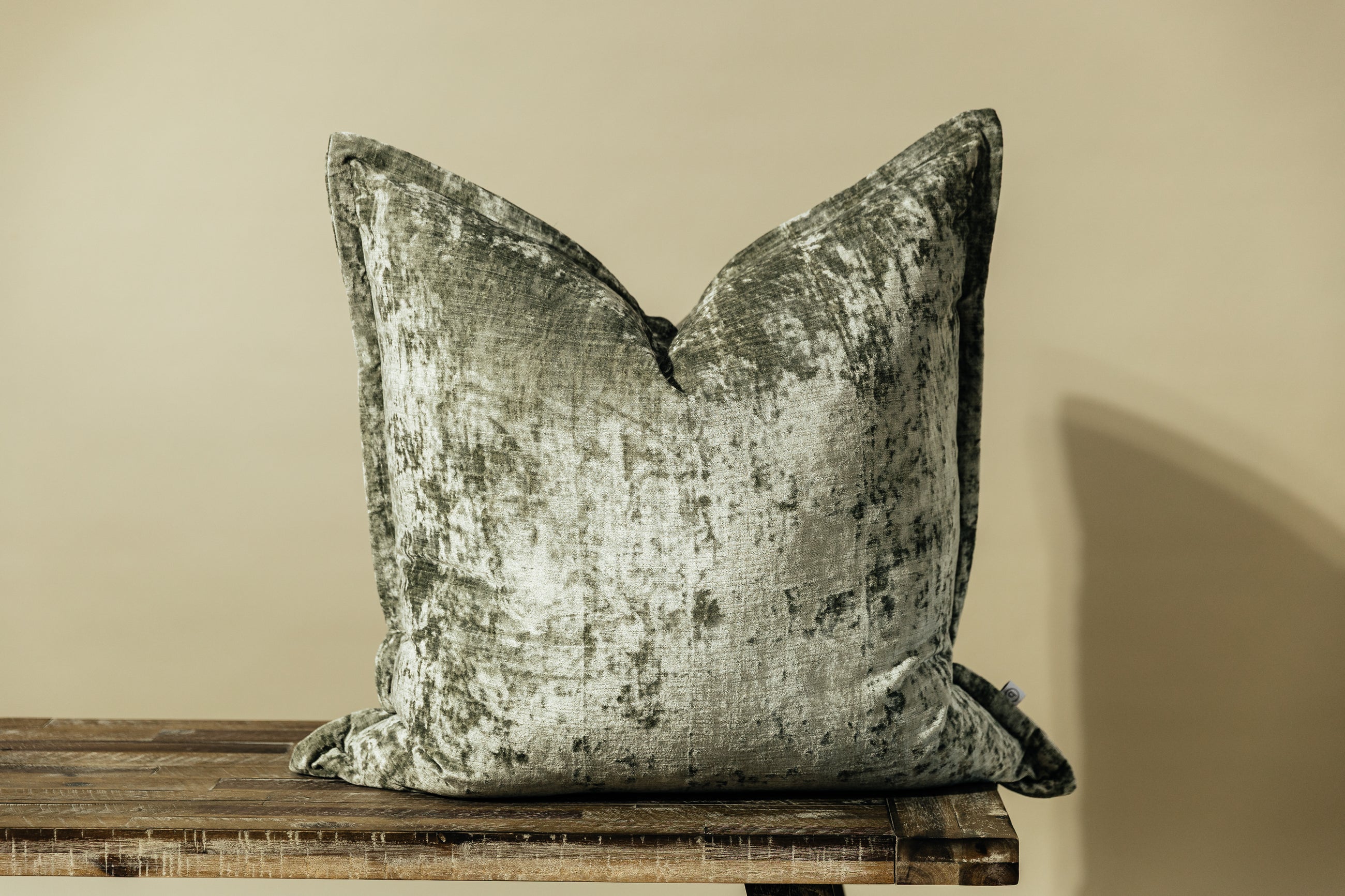 A sage velvet green XL euro pillow arranged on a bench with a light green background.