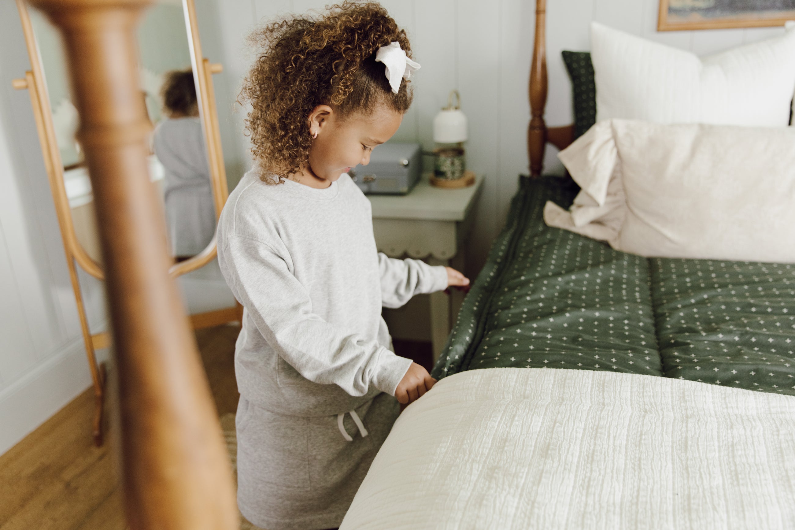 Girl zipping green bedding with white blanket on the end