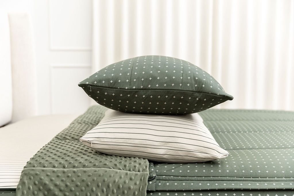 Dark green zipper bedding with small cross design with pillow sham stacked on top of pillowcase