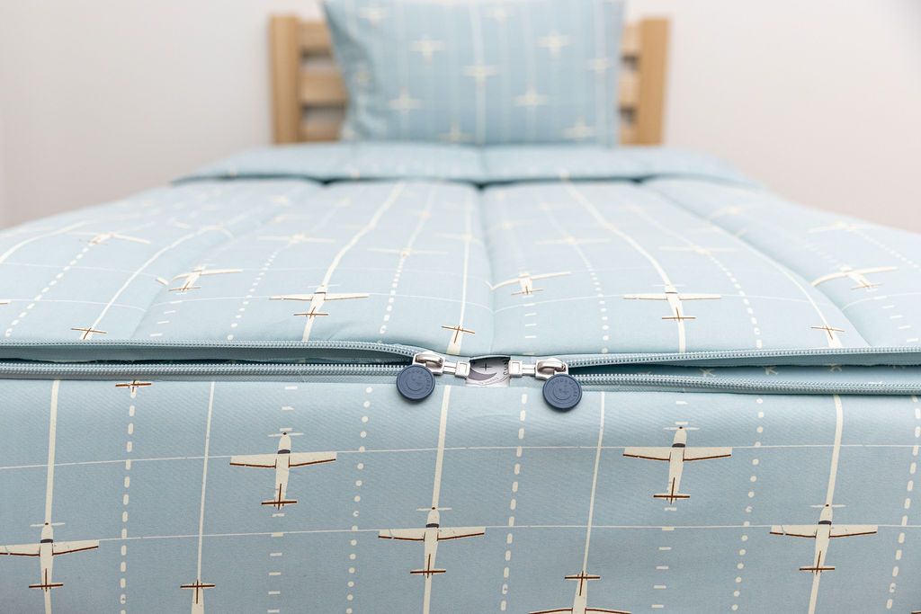 end of light blue zipper bedding with airplane design showing two zippers coming together at the end of the bed