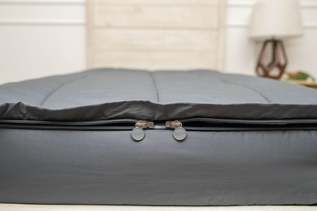 The foot of a bed made with gray zipper bedding showing where the two zippers are located.
