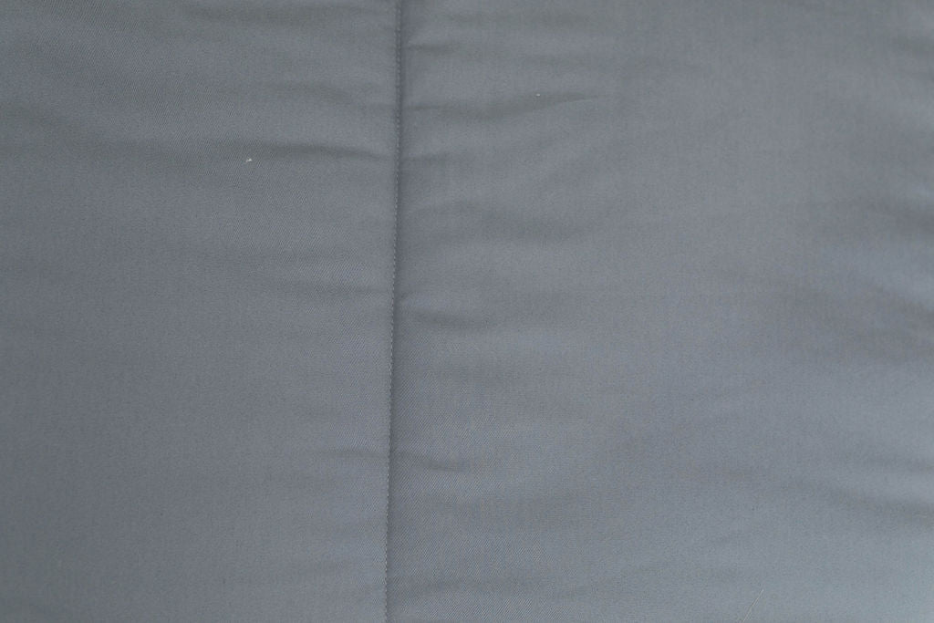 A close up detailed view of the exterior of a bed made with gray zipper bedding.
