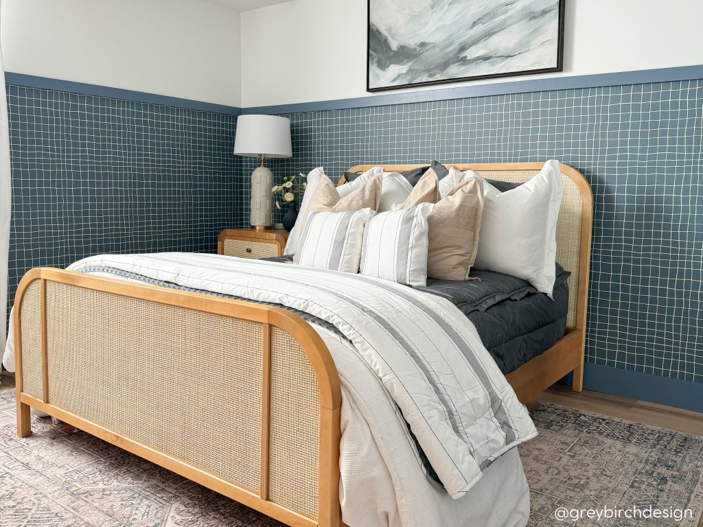 A bed made with gray zipper bedding and neutral and gray striped pillows and blankets.