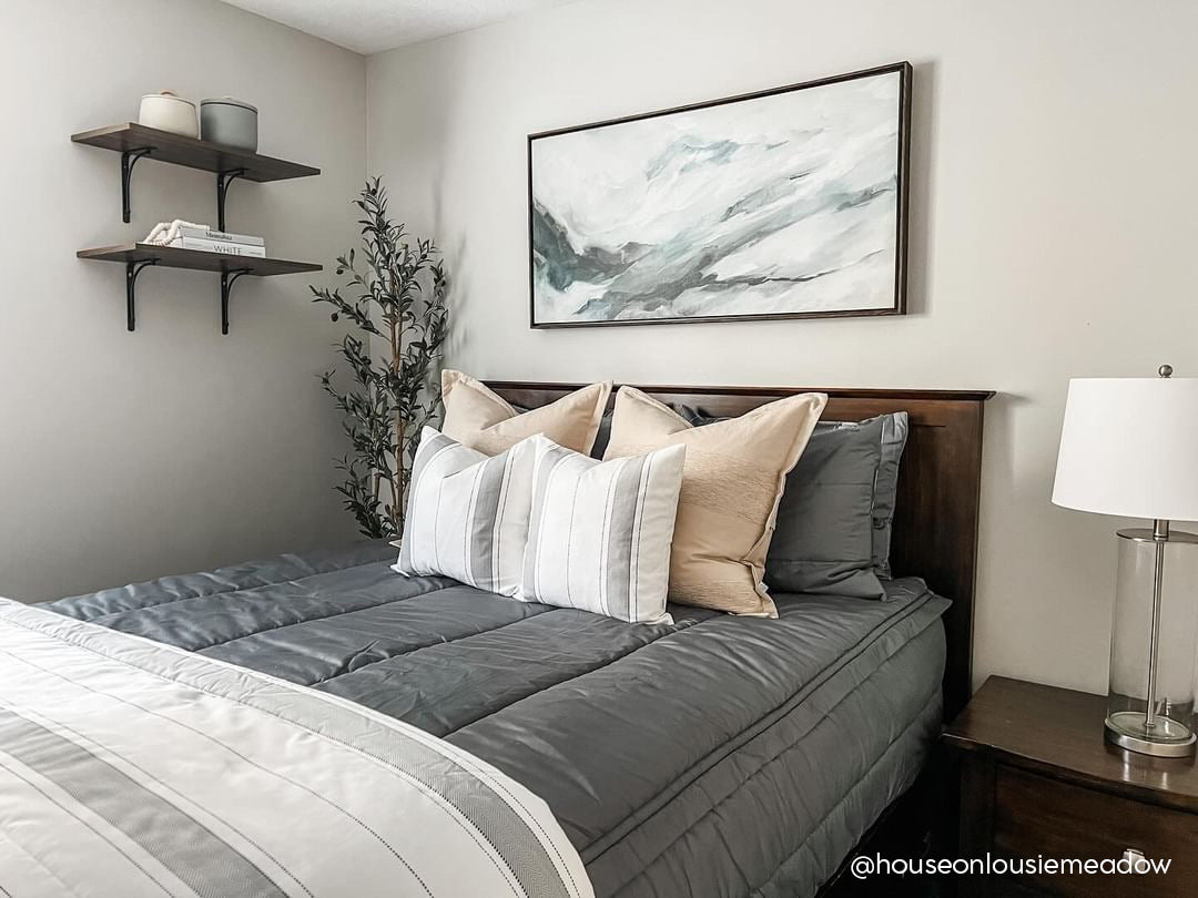 A bed made with gray zipper bedding and neutral and gray striped pillows and blanket.
