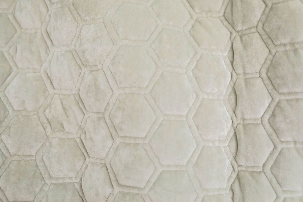 A close up of a buff gray honeycomb velvet blanket.