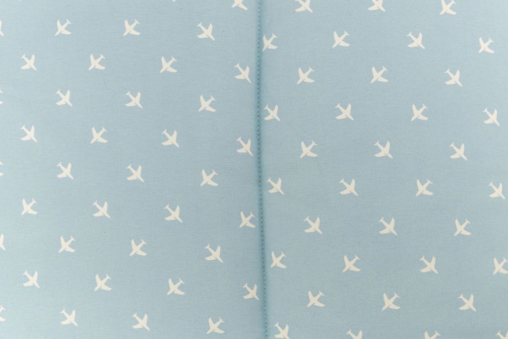 up close of light blue sheet with little white airplane design