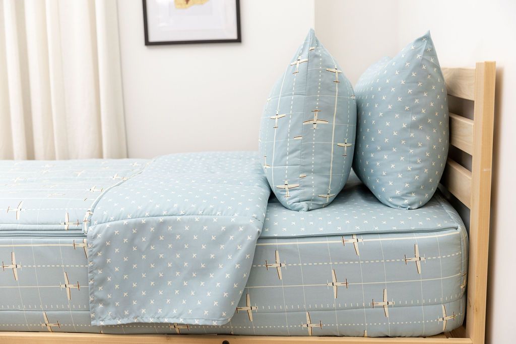 side shot of unzipped light blue zipped bedding with airplane design and coordinating pillowcase and sham