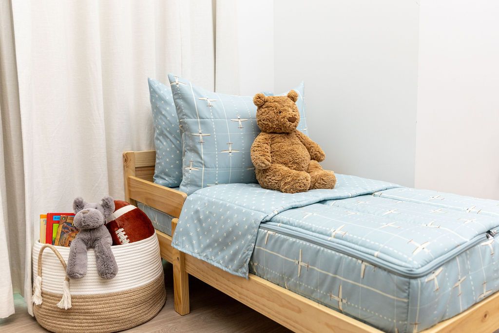 bedroom with toddler bed decorated with light blue zipper bedding and airplane design with toys on the ground