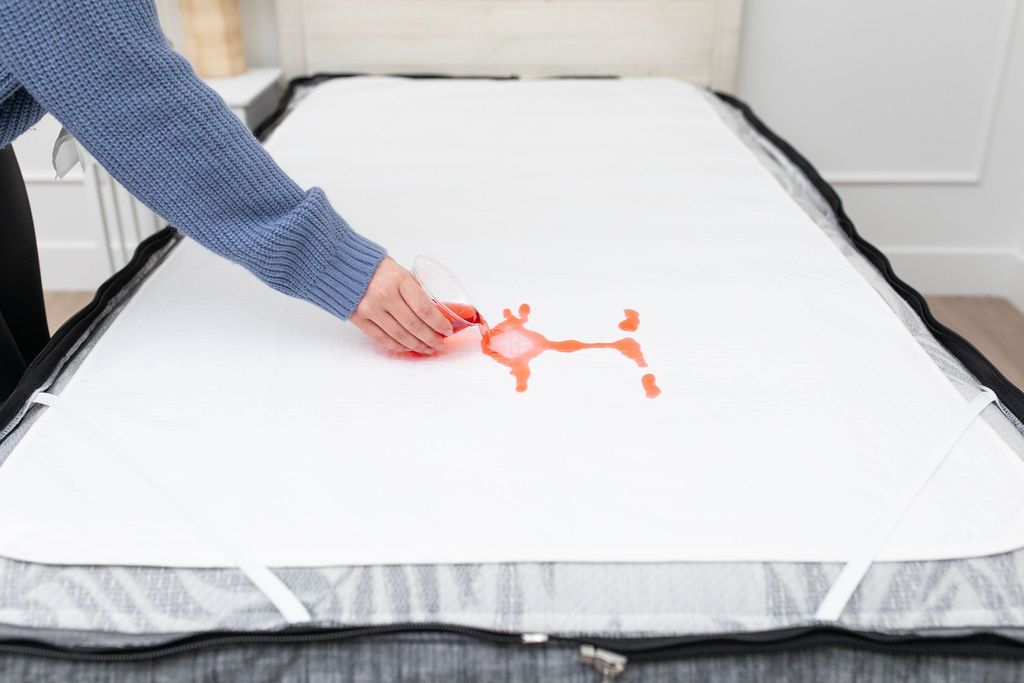 White absorbent accident bedding pad with red liquid being poured on top