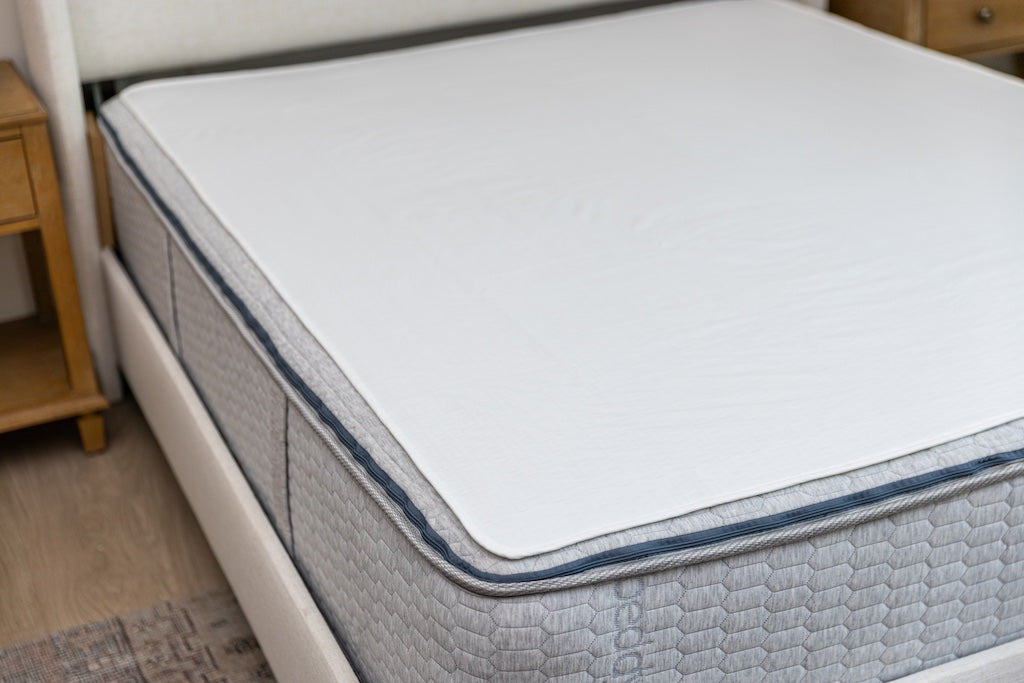 White absorbent accident bedding pad on a queen bed.