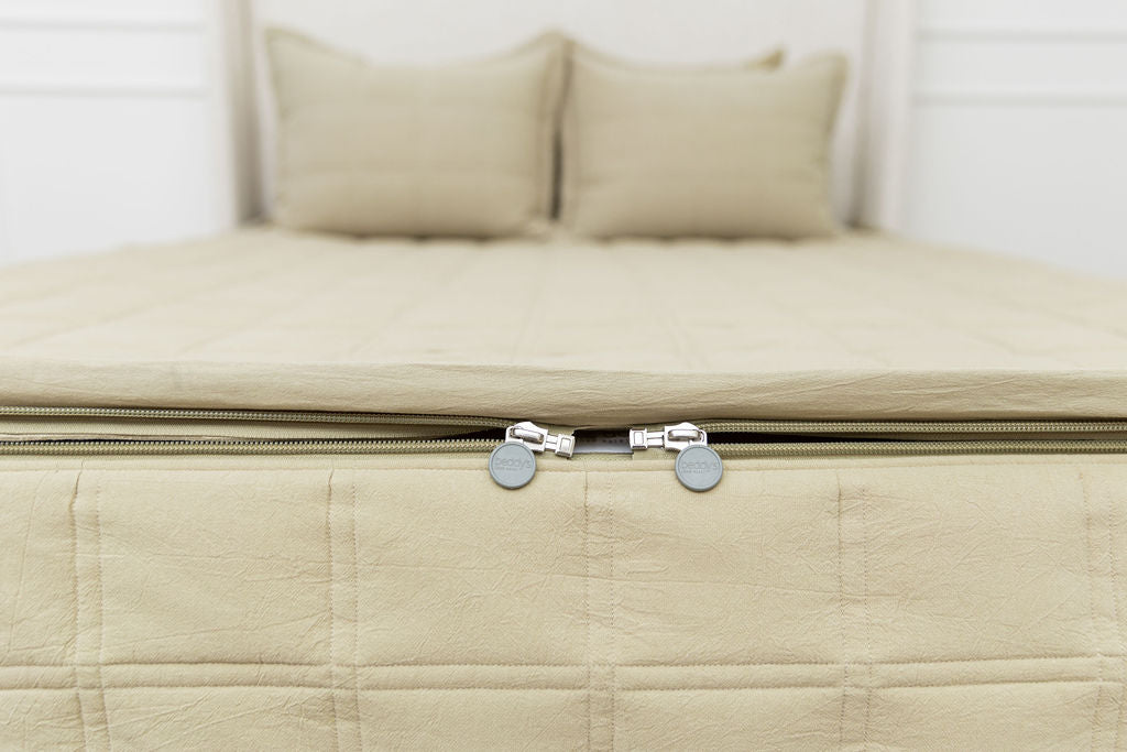 The foot of a bed made with green zipper bedding, the focus on the zipper feature of the bed.