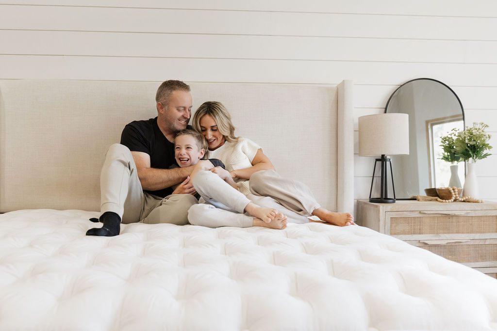 A family sitting on a king zipper mattress in a bedroom.