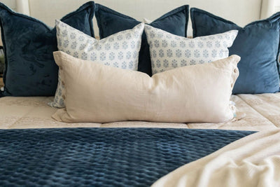 Tan zipper bedding styled with blue, tan and white pillows and blue and tan blankets