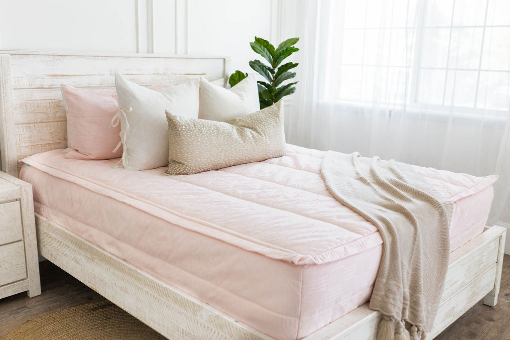 Pink zipper bedding with pink, white and cream pillows and cream throw blanket