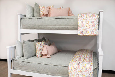 Green zipper bedding on bunk beds with pink and floral pillows and blankets