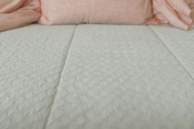 Detailed view of light sage green zipper bedding texture with pink sham pillow