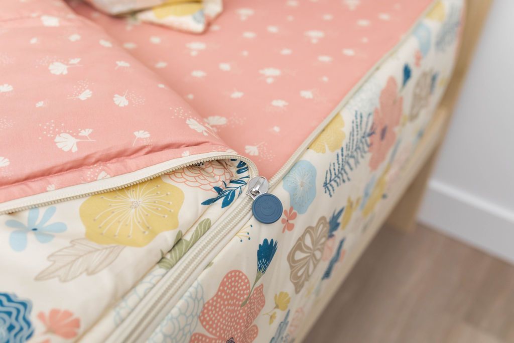 A close up on the zipper feature of a set of yellow, pink, and blue floral kids zipper bedding.