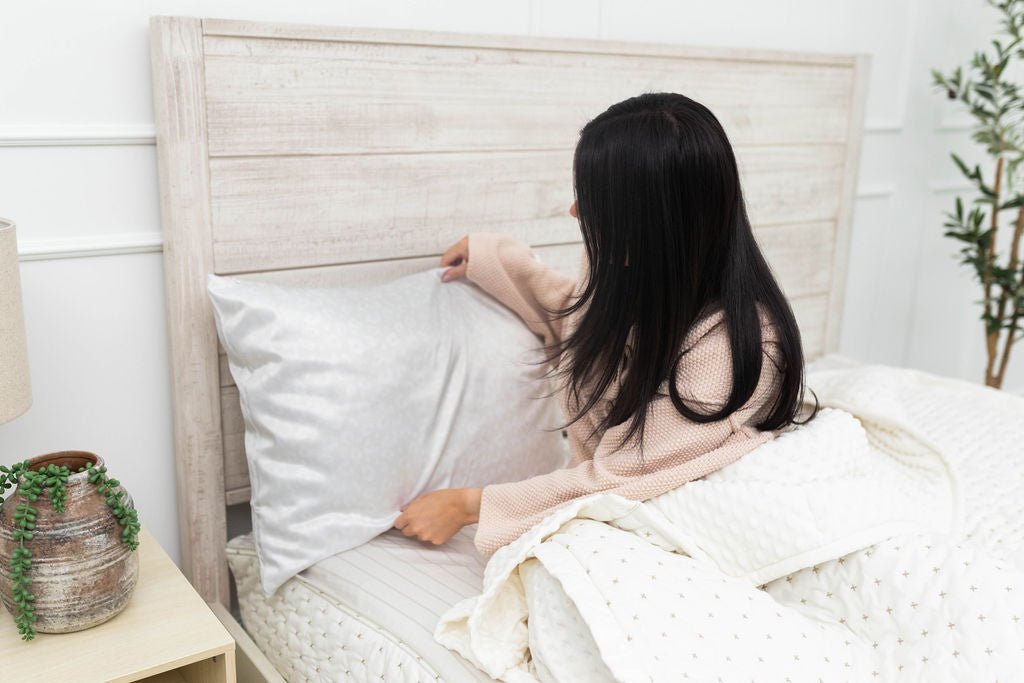 Woman adjusting satin pillowcase in bed