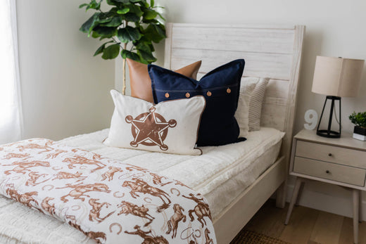 
      A twin size bed made with zipper bedding, featuring cowboy themed throw blankets and pillows.
    