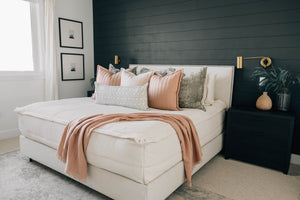 A platform bed made wih neutral zipper bedding and warm colored accessories.