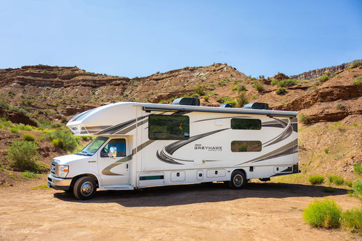 
      A white RV parked in a dessert mountainscape.
    