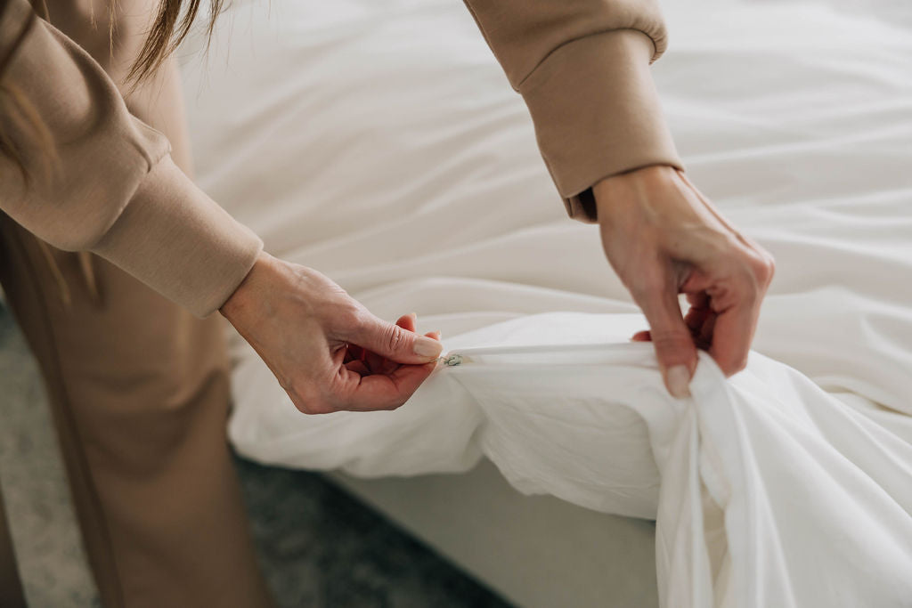 
      woman's hands unzipping white sheets bedding
    