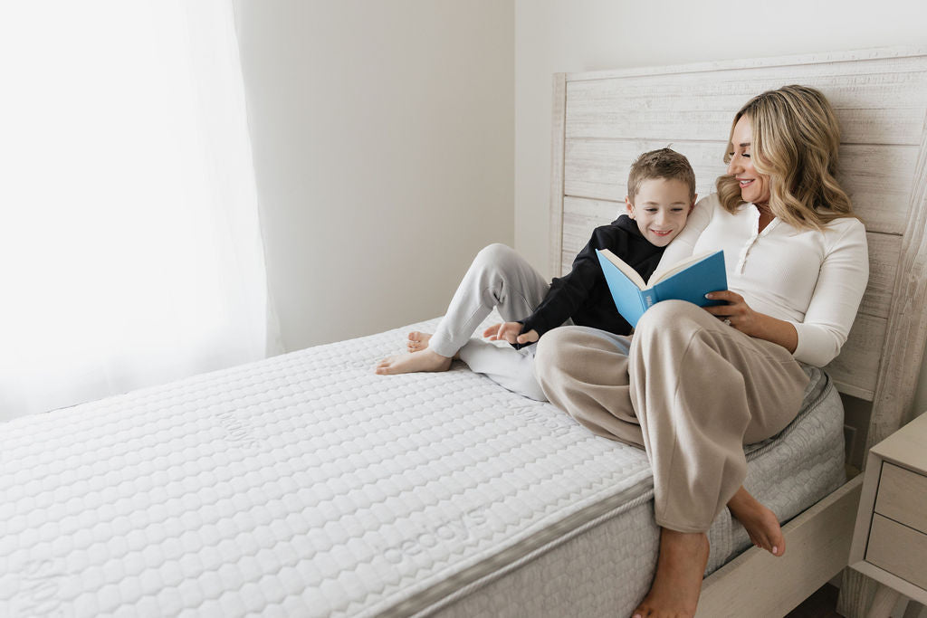 
      mother reading to son on a mattress topped bed
    