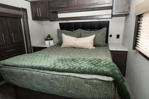 
      An RV bed made with green zipper bedding and a green velvet blanket at he foot of the bed.
    