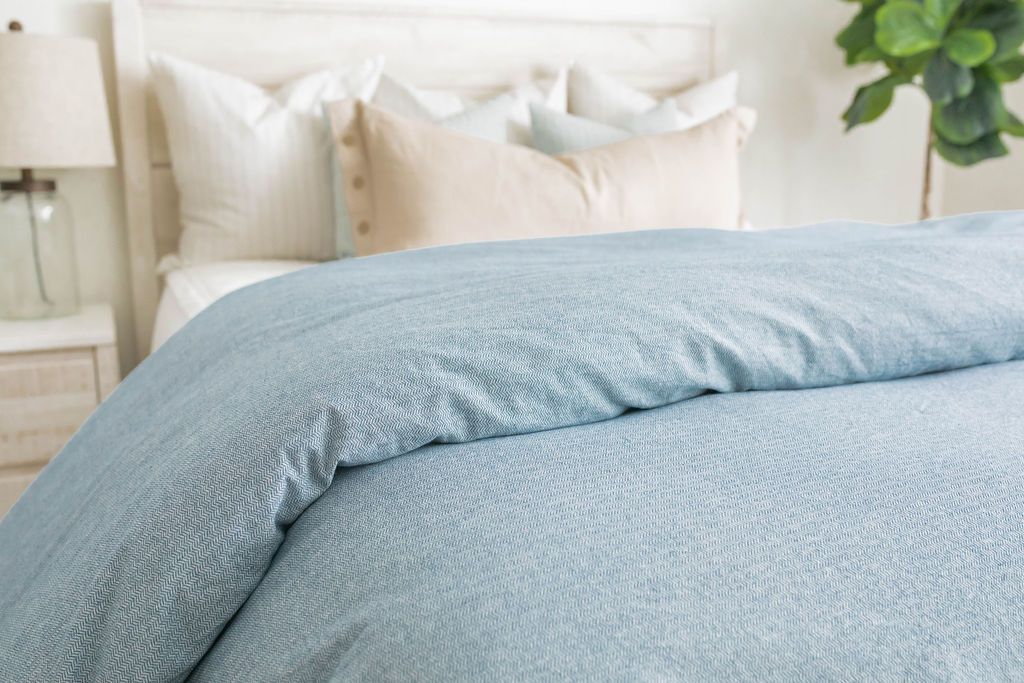 
      A side shot of a bed made with white zipper bedding and a chambray blue duvet
    