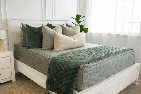 
      Bed with green and white pillows and a white nightstand, adorned with soft green zipper bedding.
    