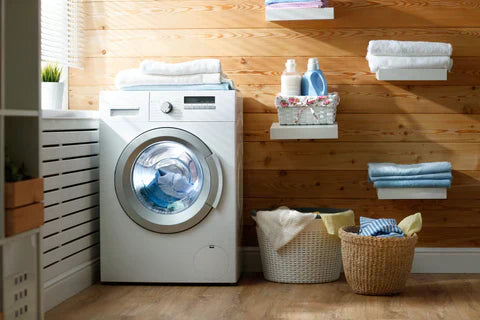 
      A brightly lit laundry room featuring a washer, baskets of clothing, and shelves of towels.
    